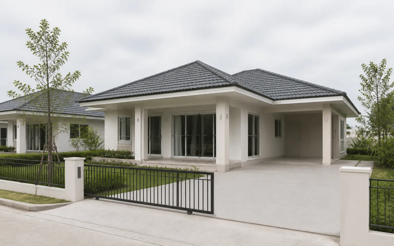 Render: House 2 three-quarter exterior — the front elevation and carport side, the covered terrace, a low front fence, a young garden, a neighbouring house of the same type past the fence.